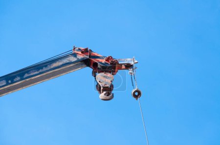 Foto de Brazo de grúa móvil con gancho colgado por cable de alambre fondo cielo azul, primer plano - Imagen libre de derechos