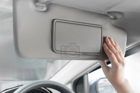 Photo for Woman hand holding sun visor interior inside car - Royalty Free Image