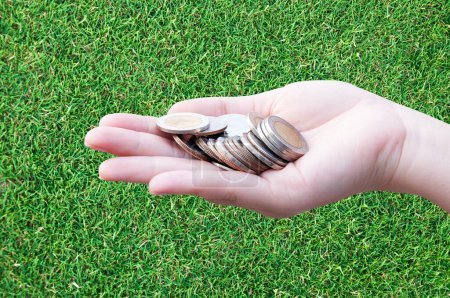 Photo for Coins in hands on grass,Donation Investment Fund Financial Support Charity  Dividend Market Growth Home House Stock Trust Wealthy Giving Planned Accounting Collection Debt Banking ROI concept - Royalty Free Image