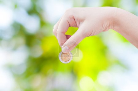 Photo for Woman hand putting a coin on green nature background,saving ,Donation Investment Fund Financial Support Charity  Dividend Market Growth - Royalty Free Image