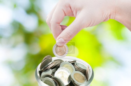Photo for Woman hand putting a coin on green nature background,saving ,Donation Investment Fund Financial Support Charity  Dividend Market Growth - Royalty Free Image