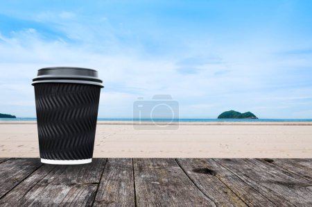 Photo for Coffee cup paper on table wooden with beach landscape view - Royalty Free Image