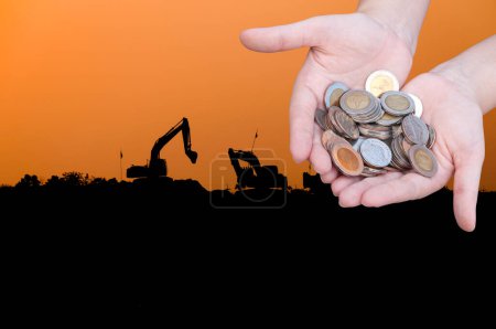 Photo for Coins in hands on Industry  silhouette Landscape background,Donation Investment Fund Financial Support Charity  Dividend Market Growth Home House Stock Trust Wealthy Giving Planned Accounting - Royalty Free Image