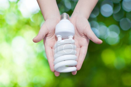 Concepto de ahorro de energía, Mujer mano sosteniendo la bombilla en el fondo de la naturaleza verde, Ideas bombilla en la mano