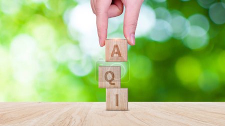 AQI, Abbreviation of air quality index word written on wooden blocks. text AQI on nature background, environment concept.