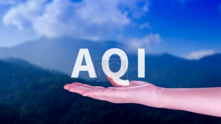 Foto de AQI, Abreviatura del índice de calidad del aire, mano que sostiene AQI en el fondo de la naturaleza, concepto del medio ambiente. - Imagen libre de derechos