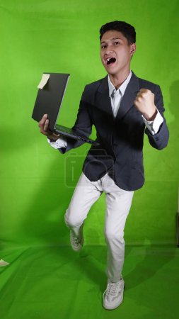 The handsome Asian young man carried a laptop with a happy expression, as if he wanted to fly and fall