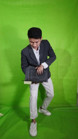 The handsome Asian youth carrying a mobile laptop with a body style expression is showing something