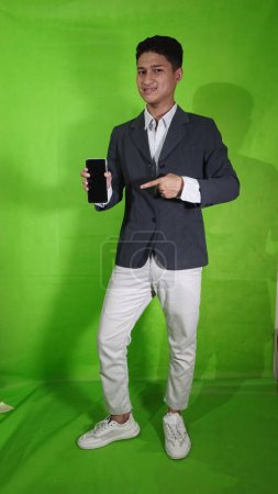 El guapo joven asiático que lleva un portátil móvil con una expresión de estilo corporal está mostrando algo