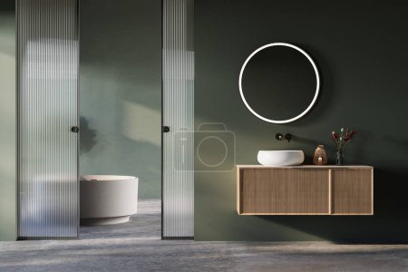 Modern bathroom interior with concrete floor, green and gray walls, vanity white sink, oval mirror, bathtub, interior plants, front view.Minimalist bathroom with modern furniture.