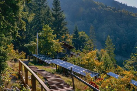 Sonnenkollektoren sind in der Nähe eines Holzhauses in einem Wald an einem Berghang installiert.
