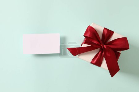 Téléchargez les photos : Vue du haut de la carte blanche avec des boîtes-cadeaux et un ruban sur fond de couleur. Noël et fête d'anniversaire - en image libre de droit