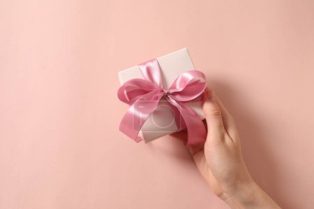 Téléchargez les photos : Femme main tenant boîte cadeau sur fond rose. - en image libre de droit