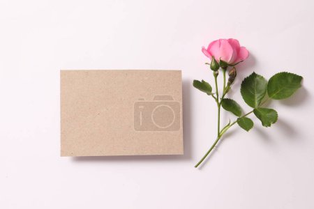 Téléchargez les photos : Blank card with pink rose flower and envelope. top view with copy space. flat lay, minimal style, mockup. - en image libre de droit