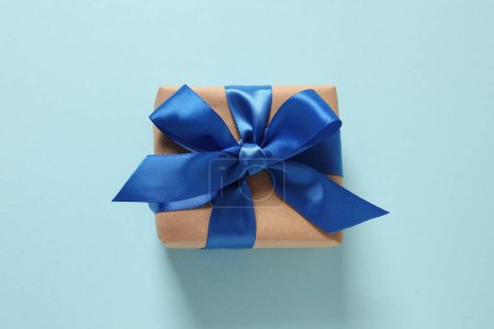 Foto de Caja de regalo azul con lazo dorado y cinta sobre un fondo azul. - Imagen libre de derechos