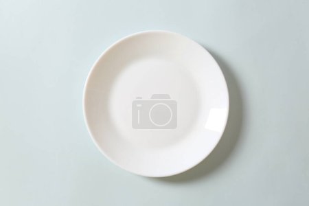 Photo for White ceramic plate on a white table, top view - Royalty Free Image