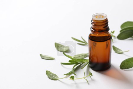 fresh essential oil in glass bottle and branch of fresh green leaves on white background.