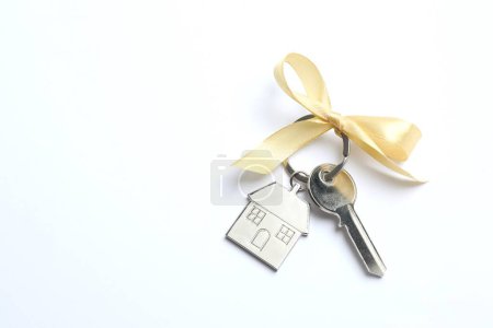 Metallic key with keychain on color background