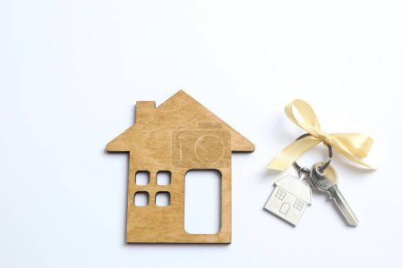 Téléchargez les photos : Clé métallique avec porte-clés et maison en bois sur fond blanc - en image libre de droit