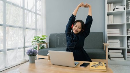 Mujer joven Asiática Relájese estirando los brazos después de estudiar en línea, después de trabajado.