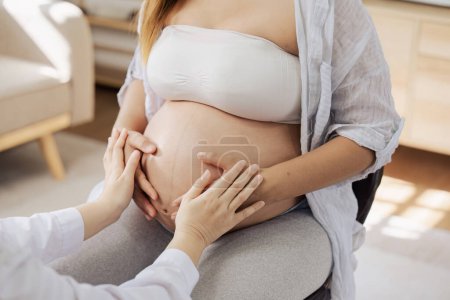 Foto de Médico tocando una barriga de mujer embarazada, sintiendo al bebé dentro de la barriga.. - Imagen libre de derechos