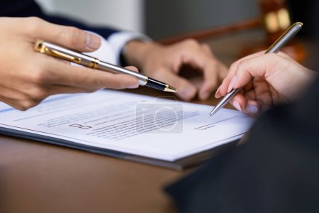 Manos de abogado señalando el papel para los empresarios que firman el contrato. Abogado, asesor legal ayudando a cliente maduro a llenar el documento.