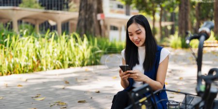 asiatische junge Geschäftsfrau benutzt Smartphone, während sie in der Stadt pendelt. Umweltfreundlich.