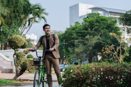 Joven hombre de negocios en traje en bicicleta parque de la ciudad para trabajar ecológico vehículo alternativo energía verde.