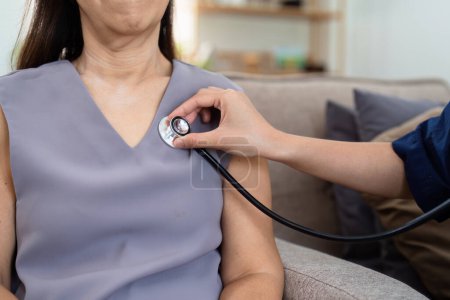 cardiologist visit elderly patient at home. cardiologist use stethoscope to listen to heart rate of elderly patient.