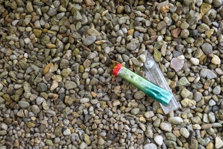 Ein grüner neonfarbener elektronischer Einwegzigarettendampf wurde aufgebrochen und auf einem Kieselstein zurückgelassen..