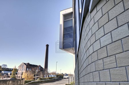 Photo for Bradford, UK 11 11 2023: A modern office building sits over a road from a victorian mill.  Both sites providing employment to the community. - Royalty Free Image