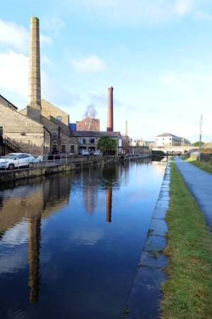 Téléchargez les photos : Shipley, Royaume-Uni 12 13 2023 : Vue du canal de Leeds Liverpool à Shipley montrant les principales cheminées réfléchissant dans l'eau du canal bleu - en image libre de droit