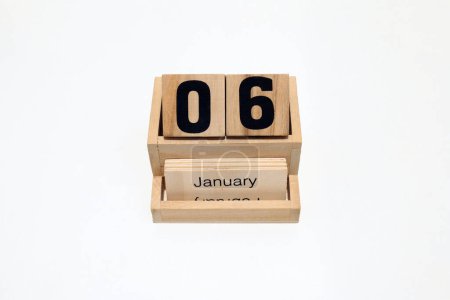 Gros plan d'un calendrier perpétuel en bois montrant le 6 janvier. Plan rapproché isolé sur fond blanc 