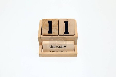 Nahaufnahme eines hölzernen ewigen Kalenders, der den 11. Januar zeigt. Nahaufnahme isoliert auf weißem Hintergrund 