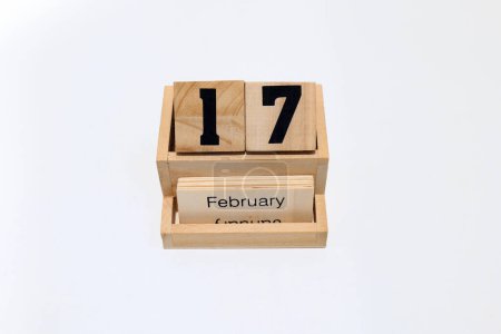 Primer plano de un calendario perpetuo de madera que muestra el 17 de febrero. Disparo de cerca aislado sobre un fondo blanco 
