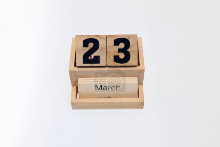 Foto de Primer plano de un calendario perpetuo de madera que muestra el 23 de marzo. Disparo de cerca aislado sobre un fondo blanco - Imagen libre de derechos