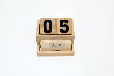 Foto de Primer plano de un calendario perpetuo de madera que muestra el 5 de abril. Disparo de cerca aislado sobre un fondo blanco - Imagen libre de derechos