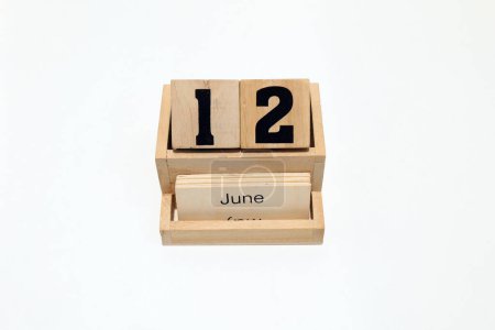 Close up of a wooden perpetual calendar showing the 12th of June. Shot close up isolated on a white background