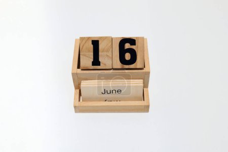 Close up of a wooden perpetual calendar showing the 16th of June. Shot close up isolated on a white background