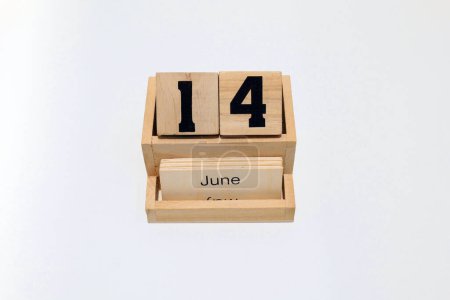 Close up of a wooden perpetual calendar showing the 14th of June. Shot close up isolated on a white background