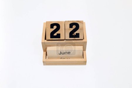 Close up of a wooden perpetual calendar showing the 22nd of June. Shot close up isolated on a white background