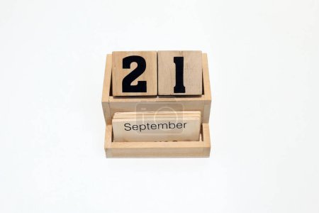 Close up of a wooden perpetual calendar showing the 21st of September. Shot close up isolated on a white background