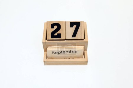 Gros plan d'un calendrier perpétuel en bois montrant le 27 septembre. Plan rapproché isolé sur fond blanc
