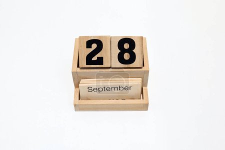 Close up of a wooden perpetual calendar showing the 28th of September. Shot close up isolated on a white background