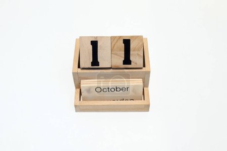Nahaufnahme eines hölzernen ewigen Kalenders, der den 11. Oktober zeigt. Nahaufnahme isoliert auf weißem Hintergrund 