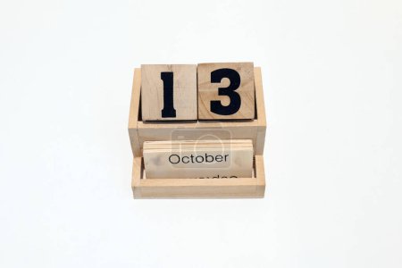 Primer plano de un calendario perpetuo de madera que muestra el 13 de octubre. Disparo de cerca aislado sobre un fondo blanco 
