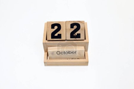 Primer plano de un calendario perpetuo de madera que muestra el 22 de octubre. Disparo de cerca aislado sobre un fondo blanco 