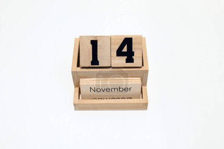 Primer plano de un calendario perpetuo de madera que muestra el 14 de noviembre. Disparo de cerca aislado sobre un fondo blanco 