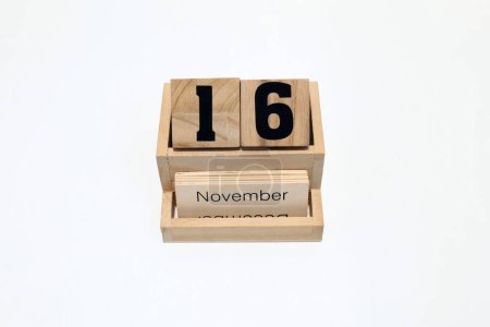 Großaufnahme eines hölzernen ewigen Kalenders, der den 16. November zeigt. Nahaufnahme isoliert auf weißem Hintergrund 
