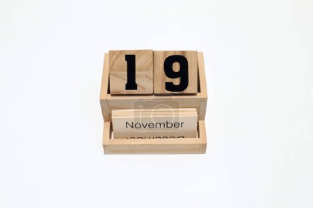 Großaufnahme eines hölzernen ewigen Kalenders, der den 19. November zeigt. Nahaufnahme isoliert auf weißem Hintergrund 